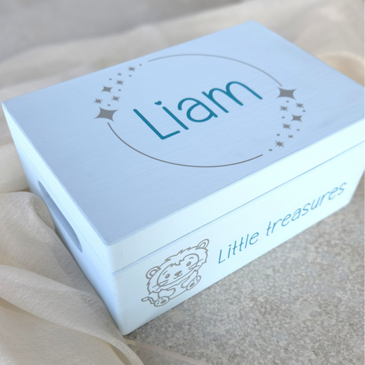 Hellblaue Baby-Erinnerungsbox aus Holz mit dem Namen „Liam“, Sternenkranz auf dem Deckel und der Aufschrift „Little treasures“ mit süssem Löwenmotiv an der Seite.