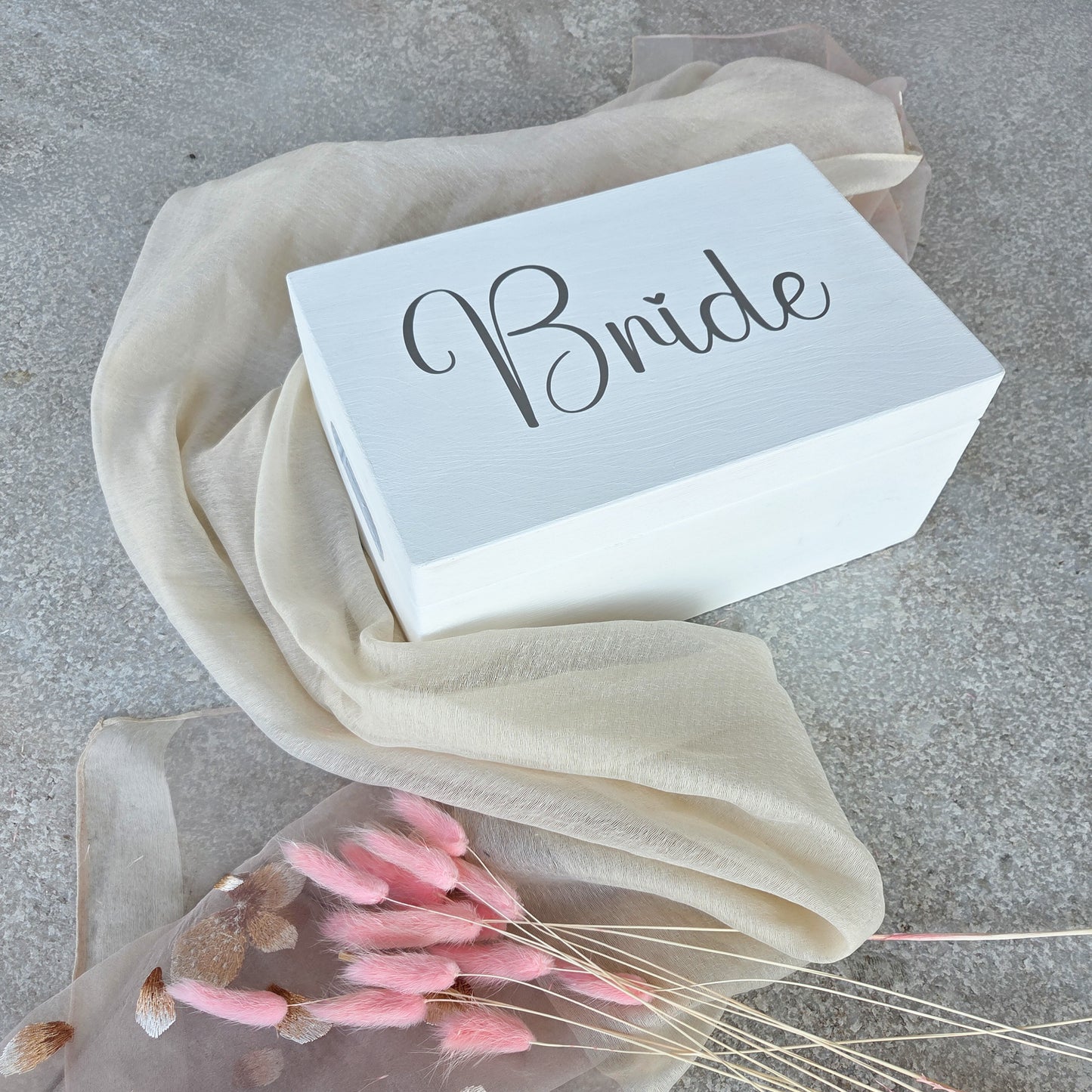 Weisse Holz-Brautbox mit dem Schriftzug „Bride“ in moderner Schrift auf hellem Tuch, ideale Erinnerungsbox für Hochzeitsfotos und Andenken der Braut.
