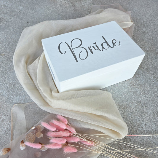 Weisse Holz-Brautbox mit dem Schriftzug „Bride“ in moderner Schrift auf hellem Tuch, ideale Erinnerungsbox für Hochzeitsfotos und Andenken der Braut.