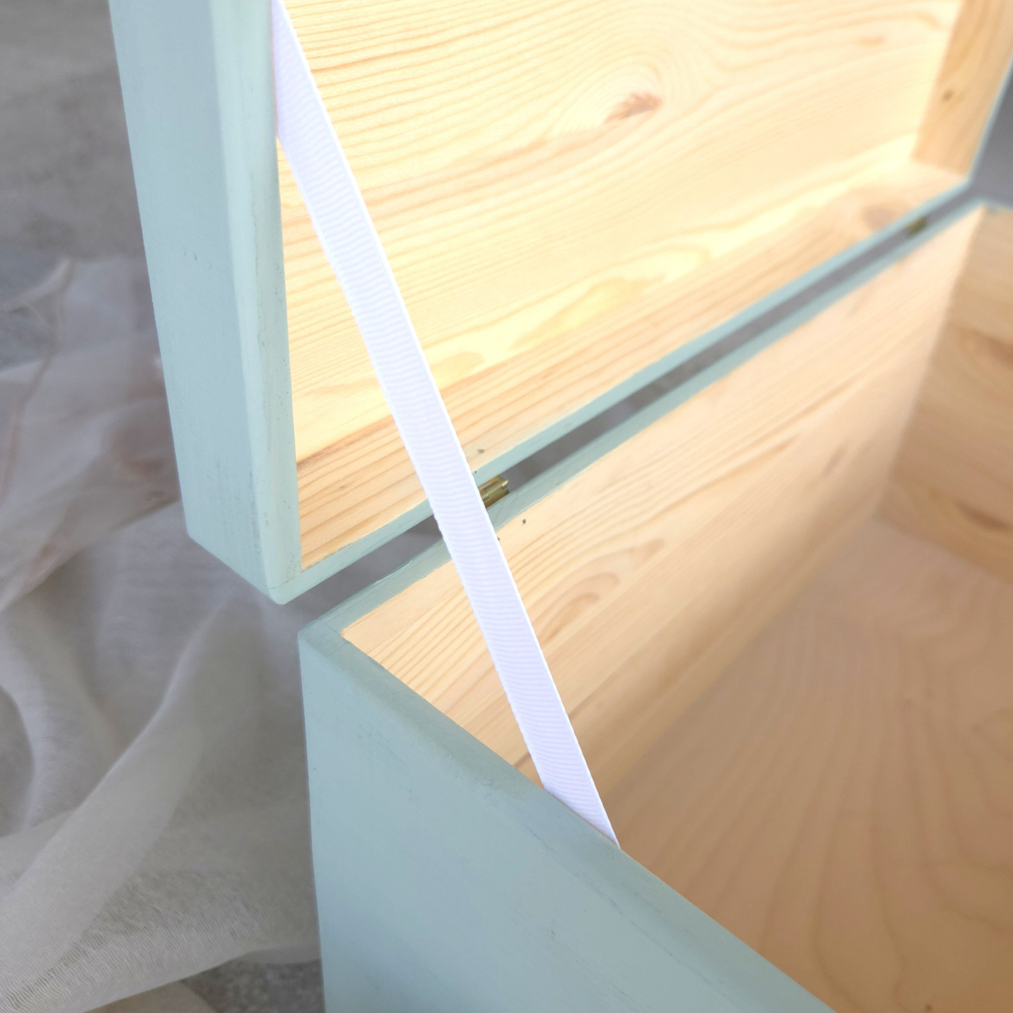 Detailansicht einer geöffneten Kita-Erinnerungsbox aus Holz mit sichtbarer Maserung und Sicherheitsband am Deckel, zeigt hochwertiges Innenleben und Verarbeitung.