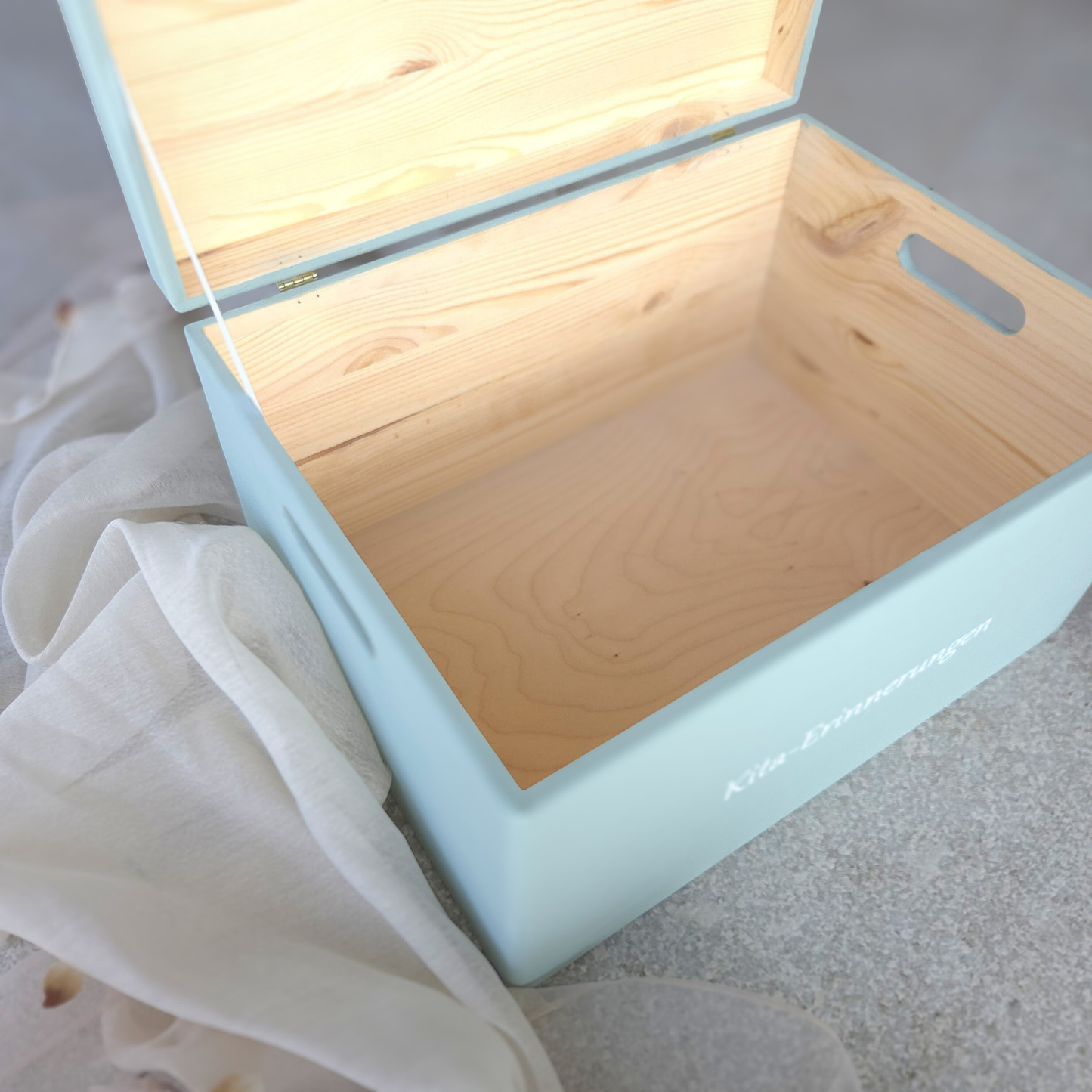 Geöffnete hellblaue Kita-Erinnerungsbox aus Holz mit grossem Innenraum, sichtbarer Holzmaserung und seitlichen Tragegriffen, ideal zur Aufbewahrung von Kita-Erinnerungen und Portfolio.